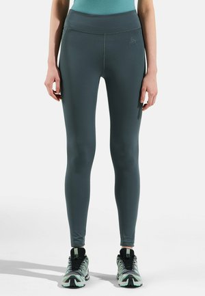 Dunkelgrüne Leggings mit hoher Taille, glatter Textur und enganliegendem Design. Verfügt über ein kleines Logo in der Nähe des Taillenbundes.