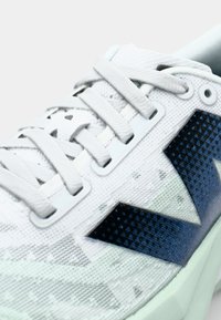 White textured sneaker with dark blue geometric pattern accents, featuring thin laces and a cushioned mint green sole.