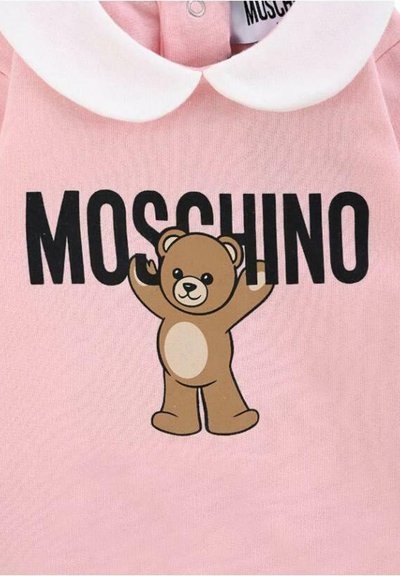Completo per neonati rosa con colletto bianco stile Peter Pan, scritta nera "MOSCHINO" e una grafica di un orsetto marrone sorridente centrata sotto il testo.
