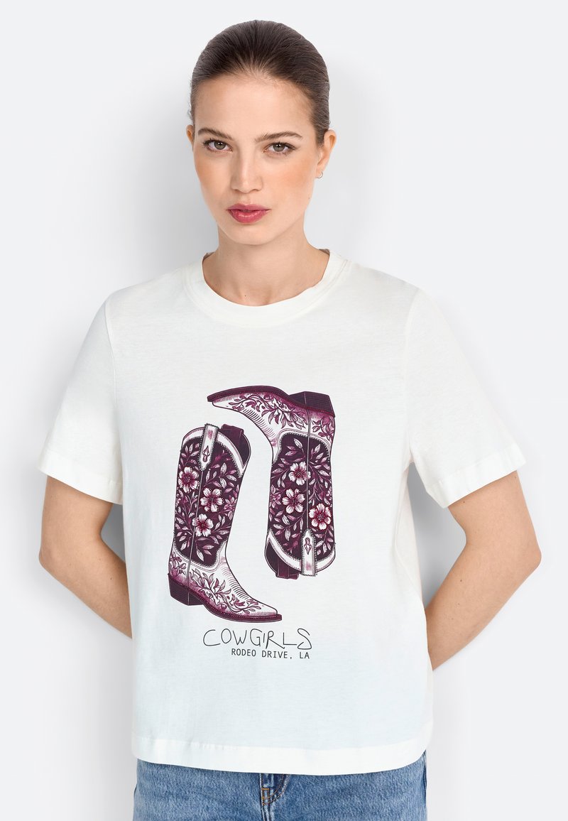 Camiseta blanca de manga corta con un gráfico de botas de vaquero moradas con patrones florales y el texto "COWGIRLS RODEO DRIVE, LA" debajo.