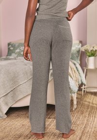 Šedé žebrované volnočasové kalhoty s volným střihem, mají zadní kapsu a vroubkovaný lem. Materiál působí měkce a pohodlně.
