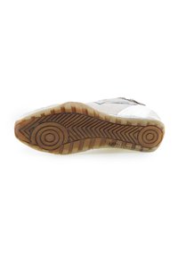 Semelle de chaussure en caoutchouc brun avec des motifs circulaires et en zigzag, couture visible, et partie d'une tige blanche et grise.