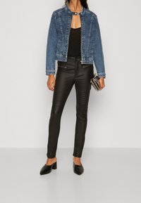 Jeansjacka med rund halsringning, blå färg och lätt slitage. Svarta läder slim-fit byxor med ribbade detaljer och ankellängd. Svarta klack-mules.