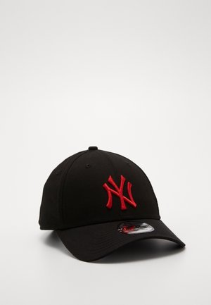Czarna czapka baseballowa z zakrzywionym daszkiem oraz czerwonym, haftowanym stylizowanym logo NY z przodu, leżąca na gładkiej białej powierzchni.