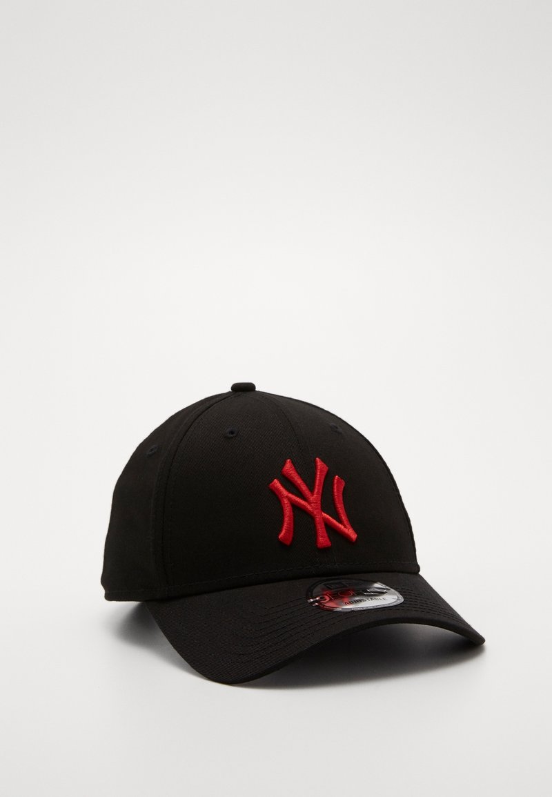 Casquette de baseball noire avec une visière courbée et un logo NY stylisé brodé en rouge sur le devant, reposant sur une surface blanche unie.
