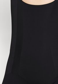 Μαύρο σορτσάκι με απαλό, ελαστικό ύφασμα και υφασμάτινα πανάκια στο πλάι. Στρογγυλή λαιμόκοψη και καθαρές ραφές.