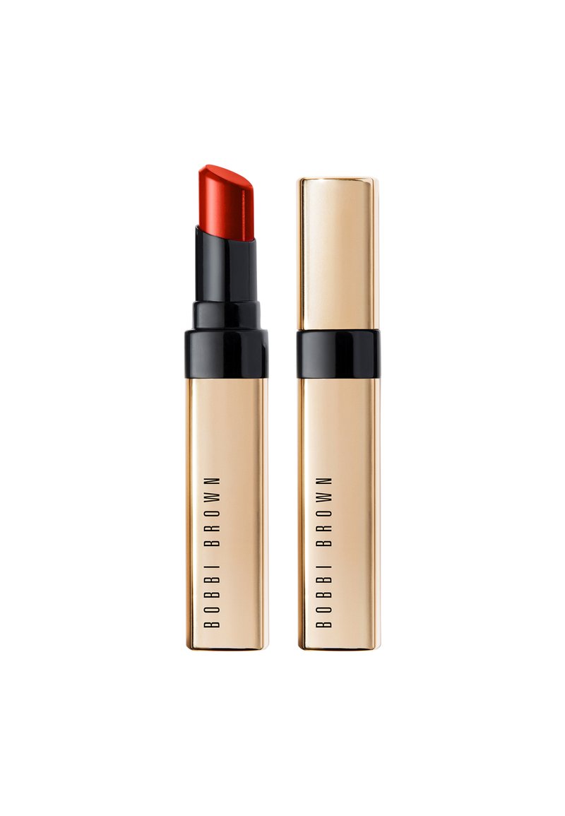 Roter Lippenstift in einem goldenen und schwarzen Gehäuse. Die Mine ist scharfkantig und das Gehäuse weist ein minimalistisches Branding auf. Glatte, metallische Textur.