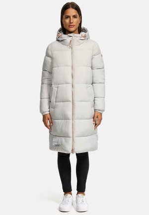 Veste matelassée gris clair avec capuche, dotée d'une fermeture éclair sur le devant, de poches latérales et de quincaillerie décorative. Portée sur un jean foncé et des baskets blanches.