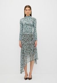 Kukalliset pitkähihainen mekko sinisen ja vihreän sävyissä, jossa on epäsymmetrinen helma, läpinäkyvä rakenne ja tiukka bodice. Ruskeat teräväkärkiset kengät.