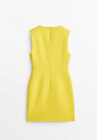 Robe jaune sans manches à la silhouette ajustée, col rond et fermeture éclair discrète dans le dos. Tissu lisse et lignes épurées mettent en valeur son design.