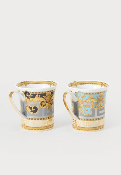 Zwei dekorative Tassen mit glänzender Oberfläche. Eine hat eine graue Basis mit goldenen Akzenten und filigranen Mustern; die andere hat eine blaue Basis.