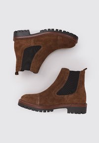 Braune Wildleder-Ankleboots mit elastischen Seiteneinsätzen und strukturierten Gummisohlen. Sie verfügen über eine abgerundete Zehenpartie und ein minimalistisches Design. Keine sichtbaren Beschläge.