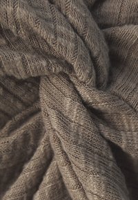 Tissu tricoté marron avec un motif en diamant texturé, mettant en valeur un matériau doux et chaud qui semble épais et confortable.