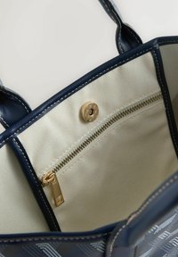 Navy bag with a textured design, golden zipper closure, and interior pocket. Fabric lining in light beige with stitching details.