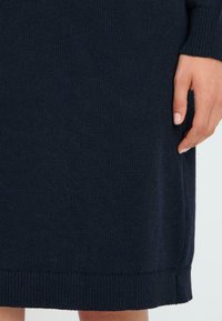 Pletené šaty v tmavo námorníckej modrej farbe, s textúrovaným povrchom, rebrovanými manžetami a lemom s jemným, hladkým finišom.