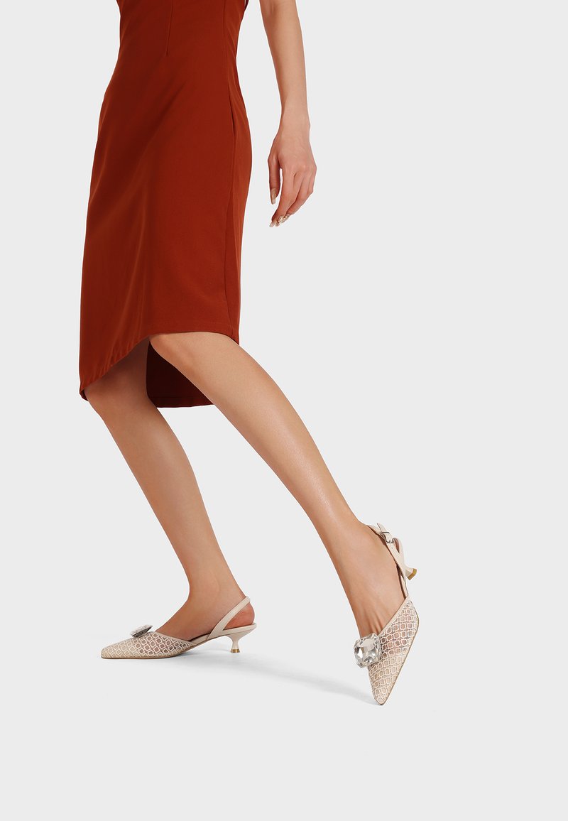 Tacchi slingback beige con un motivo a diamante, punta affusolata, tacco kitten piccolo e dettaglio a fiocco decorativo sulla parte anteriore.