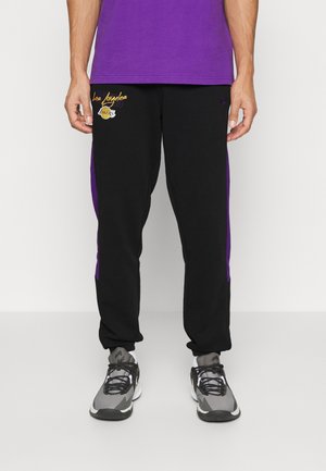 Mann trägt schwarze und lila Los Angeles Lakers Jogginghose mit grauen und schwarzen Sportschuhen.
