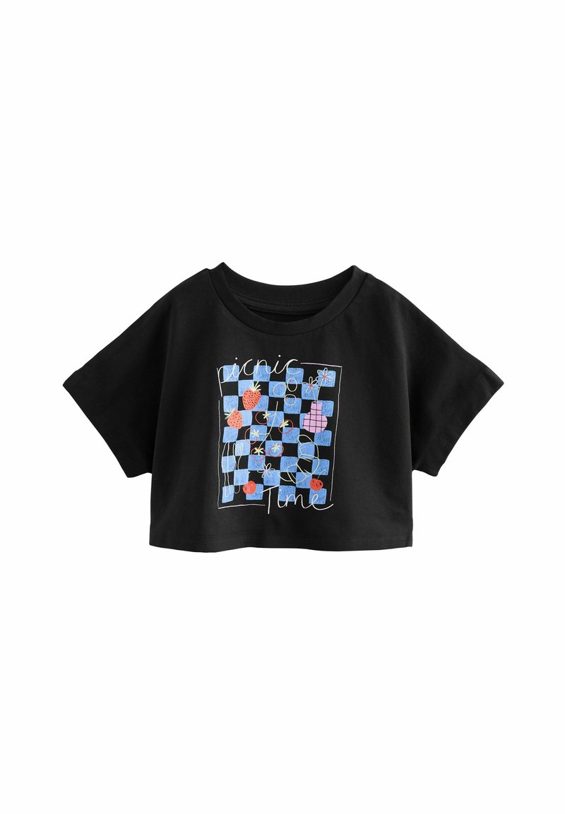 Crop top noir avec un col rond. Présente un graphique coloré sur le thème d'un pique-nique avec des fraises et des fleurs sur un fond à carreaux bleus.