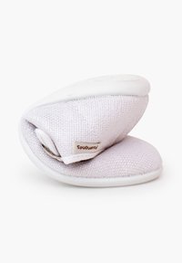 Chaussure bébé en tissu blanc texturé pliée avec une petite étiquette beige attachée sur un fond blanc uni.