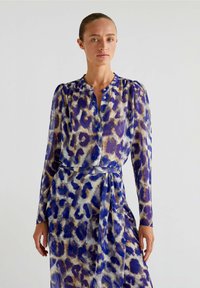 Abito trasparente con stampa animale nei colori viola, blu e beige. Presenta maniche lunghe, un collo a bottoni e una vita con cintura per un silhouette aderente.