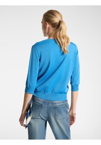 Maglione blu lavorato a maglia con maniche tre quarti, scollatura rotonda e orlo a costine adattato. Accentuato da una sottile texture scintillante.