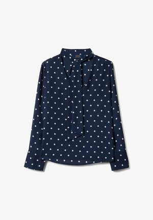 Marineblaue langärmlige Bluse mit weißen Polka-Dots und einem gebundenen Halsschal-Detail, flach auf weißem Hintergrund liegend.