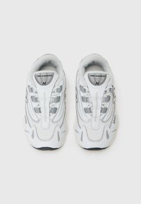 White mesh and leather sneakers with gray accents, featuring a padded collar, textured soles, and reflective detailing on the sides.