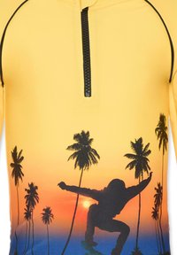 Korte mouw gele rash guard met zwarte rits, met een gradient zonsondergang ontwerp en de silhouet van een skateboarder tussen palmbomen.