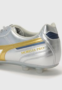 Ezüst sz�ínű focicipő, fényes felülettel. Arany csíkkal, sötétkék részletekkel és "MORELIA PRO" logóval rendelkezik. Texturált felület, látható varrással.