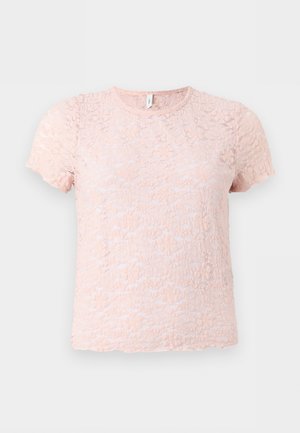 Blouse en dentelle rose clair à manches courtes avec motif floral et encolure ronde sur fond uni gris clair.