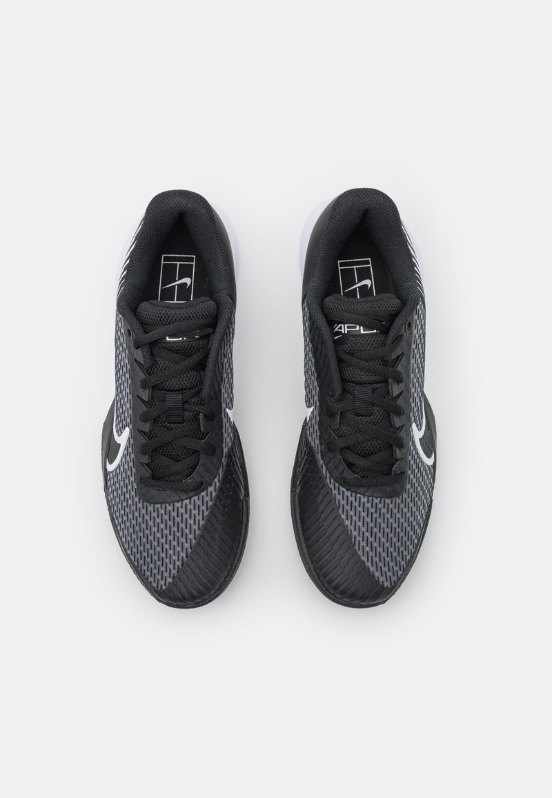 Baskets de sport noires avec une tige en maille texturée, arborant un logo Nike blanc, des lacets noirs et une semelle en caoutchouc avec un motif.