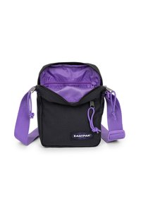 Sort crossbody taske med lilla accenter, lynlåslukning, justerbar strop og en indvendig stofforet lomme. Eastpak-logoet synligt.