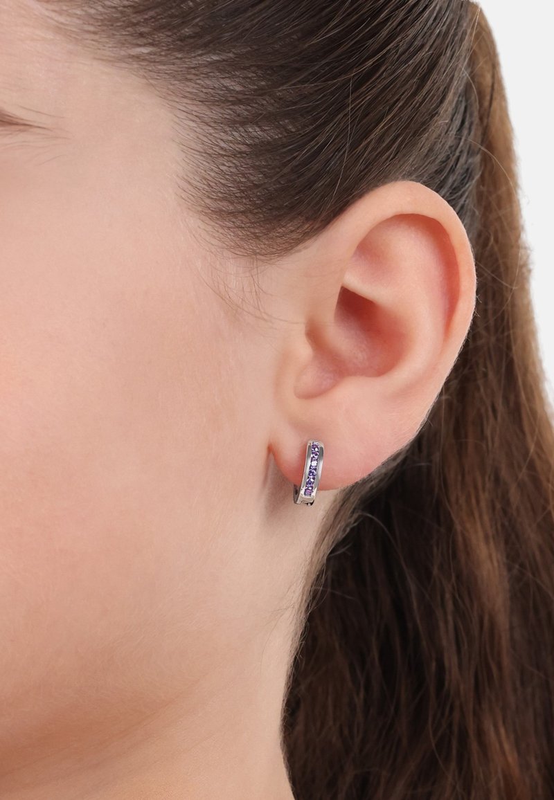 Orecchini a cerchio argento con pietre viola, superficie lucida, forma rotonda e design minimalista, indossati all'orecchio di un modello.