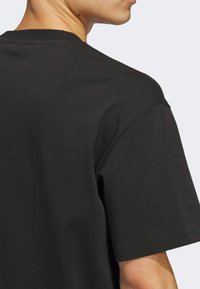 Black cotton t-shirt featuring a round neckline and short sleeves, with a smooth texture and minimal stitching details.