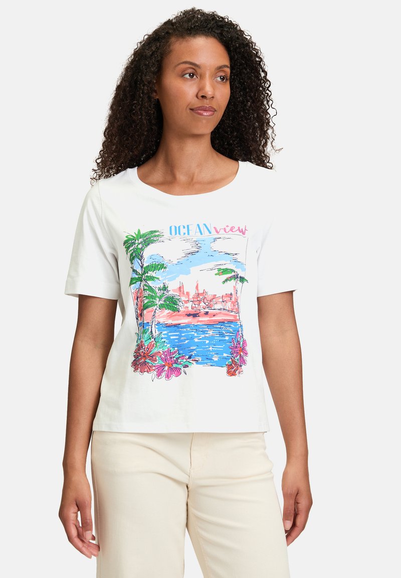 Hvid bomulds T-shirt med farverig grafik af palmer, blomster og en kystscene med teksten "OCEAN view". Korte ærmer, rund hals.