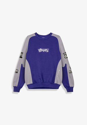 Sudadera morada y gris con mangas largas, puños acanalados, cuello redondo y diversos gráficos impresos y texto en las mangas y en el frente.