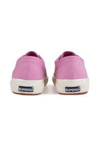 Des chaussures slip-on en toile rose avec une tige texturée, une semelle en caoutchouc crème et un logo sur le talon. Bout rond et design minimaliste.