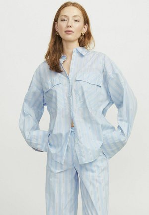 Chemise à rayures bleues et blanches à boutons avec deux poches sur la poitrine, coupe ample et manches longues, assortie à un pantalon ample.