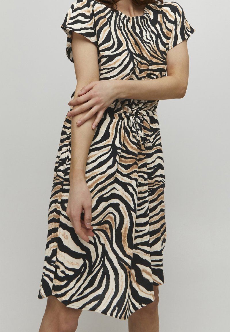Kleid mit kurzen Ärmeln in einem Zebra-Muster in Schwarz, Creme und Beige. Gathered-Ausschnitt und ein taillierter Bindegürtel. Glatte Stofftextur.