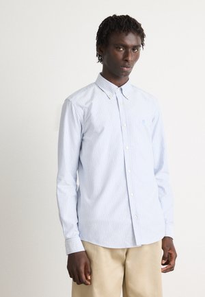 Light blue and white striped button-up shirt with a standard collar, long sleeves, and a curved hemline. Features a small logo on the chest.