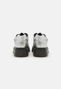 Srebrne buty typu low-top z teksturowaną cholewką, z czarną gumową podeszwą i wyciętym designem pięty. Gładkie wykończenie z subtelnymi detalami w postaci stichingu.