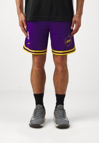 Vijolične košarkarske hlače z rumenimi črtami na robu in logotipom NBA. Na sprednji strani so grafike "Lakers", izdelane iz zračnega materiala.