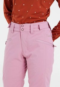 Svetloružové lyžiarske nohavice s hladkou textúrou, obsahujúce dve predné vrecká, pútka na opasok a dvojité gombíky na páse.