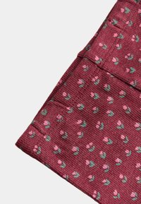 Tela burdeos doblada con un pequeño estampado floral rosa y sutiles hojas verdes, mostrando bordes cosidos y textura suave.