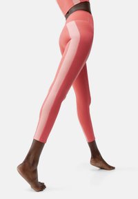 Roze legging met een nauwsluitend ontwerp, voorzien van contrasterende lichterroze zijpanelen en een gladde, rekbare textuur.