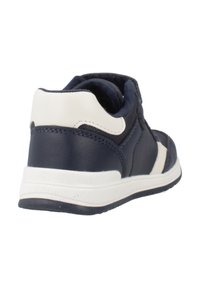Sneaker blu navy con accenti bianchi, dotata di tomaia in pelle testurizzata, colletto imbottito e suola in gomma. La vista posteriore mette in evidenza il design.