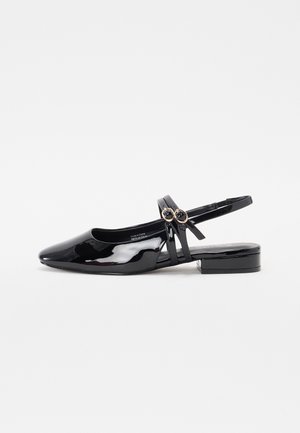 Scarpa slingback in pelle verniciata nera con punta affusolata, tacco basso e due fibbie circolari decorative sulla cinghia regolabile.