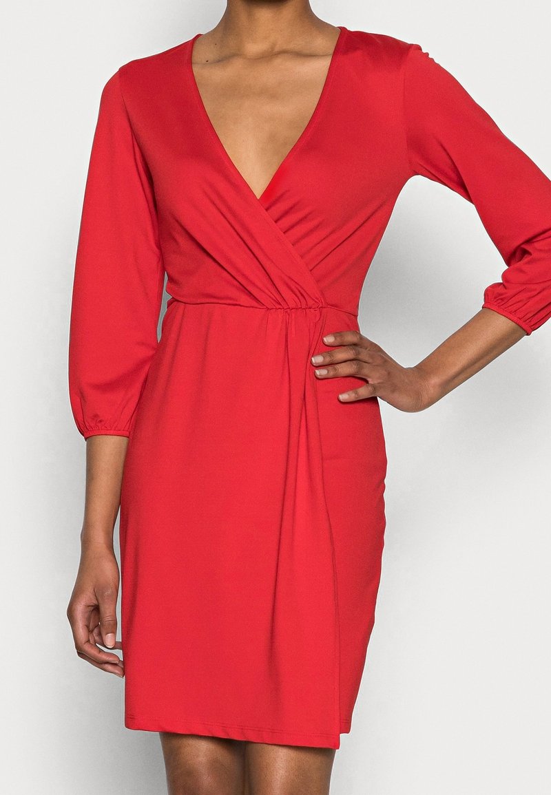 Robe portefeuille rouge avec manches trois-quarts, décolleté plongeant en V, détail de taille froncée, en tissu lisse, avec une coupe jusqu'au genou.
