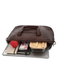 Braune Ledertasche teilweise geöffnet, zeigt Laptop, Smartphone, Notizbücher, rotes Tuch und Lebensmittelbehälter mit Bambusdeckel innen.