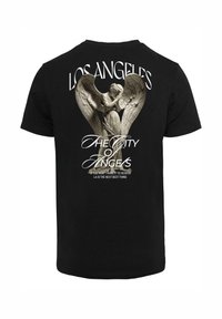 T-shirt en coton noir avec un grand imprimé représentant un ange et le texte "LOS ANGELES, LA VILLE DES ANGES" en blanc et gris.
